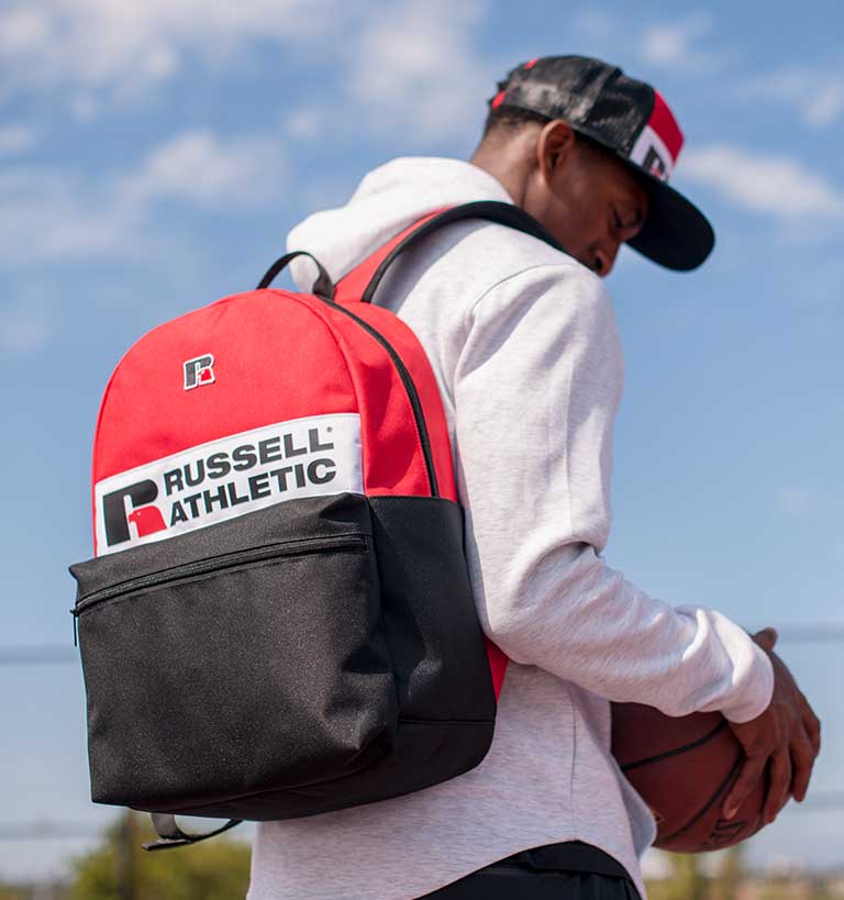 Male model in black sweatshirt holding a black duffle bag.